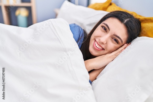 Young beautiful hispanic woman smiling confident lying on bed at bedroom