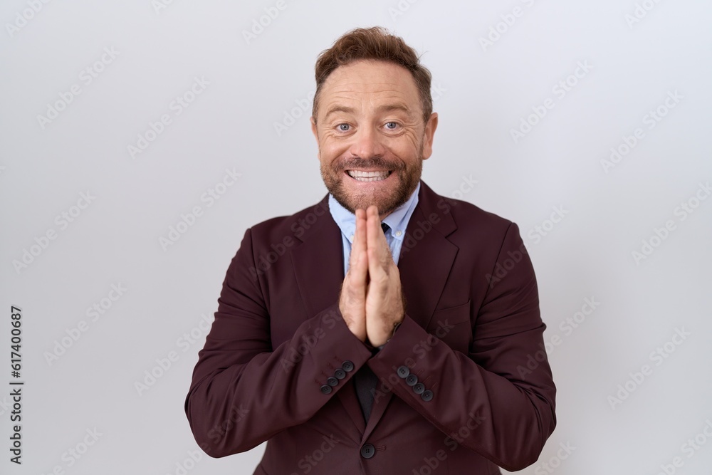 Middle age business man with beard wearing suit and tie praying with hands together asking for forgiveness smiling confident. Middle age business man with beard wearing suit and tie praying with hands together asking for forgiveness smiling confident.
