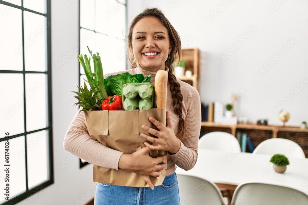 Young beautiful hispanic woman smiling confident holding groceries bag at home Young beautiful hispanic woman smiling confident holding groceries bag at home