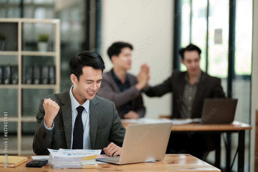 Young handsome asian businessman success working in the office looking to a computer. Young handsome asian businessman success working in the office looking to a computer.
