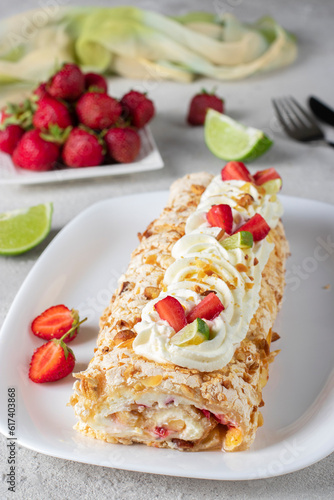 Meringue roll with strawberries and lime on light gray background, Vertical image