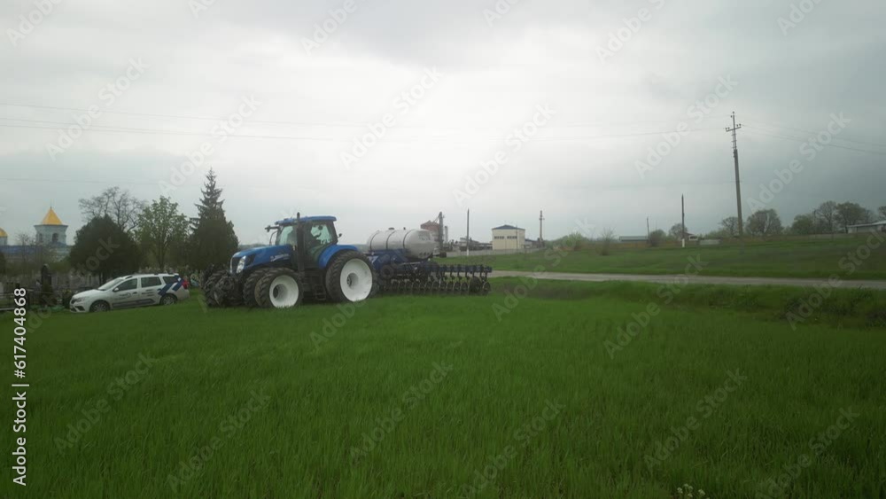 Blue tractor working on the wheat field doing liquid fertilizer injection Blue tractor working on the wheat field doing liquid fertilizer injection