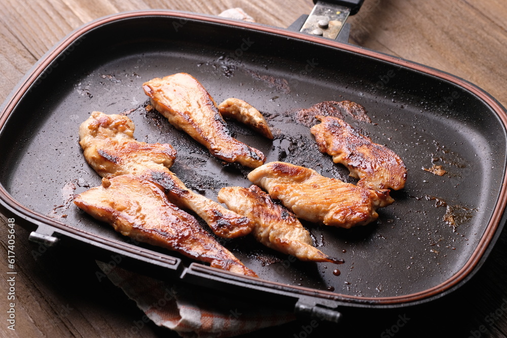 chicken steak on a black teflon pan on wooden table. non stick pan. chicken steak on a black teflon pan on wooden table. non stick pan.