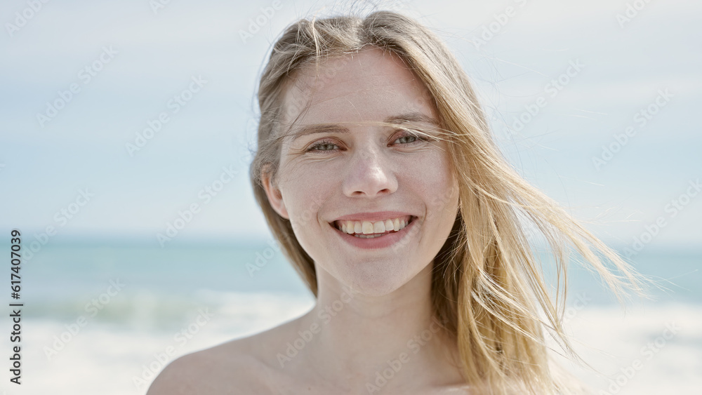 Young blonde woman tourist smiling confident standing at beach