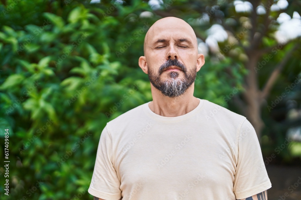 Young bald man breathing with closed eyes at park Young bald man breathing with closed eyes at park