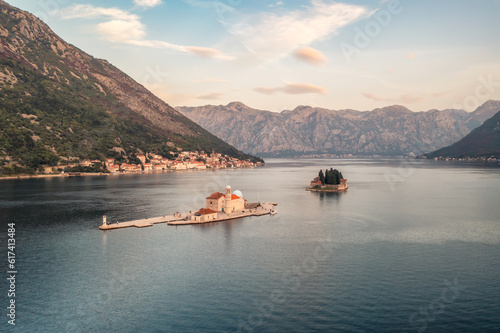 Aerial panoramic view of the island Our Lady of the Rocks and island of St. George near the picturesque town of Perast in the waters of the Bay of Kotor during the golden hour of sunset, Montenegro.