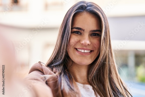 Young beautiful hispanic woman smiling confident making selfie by camera at street