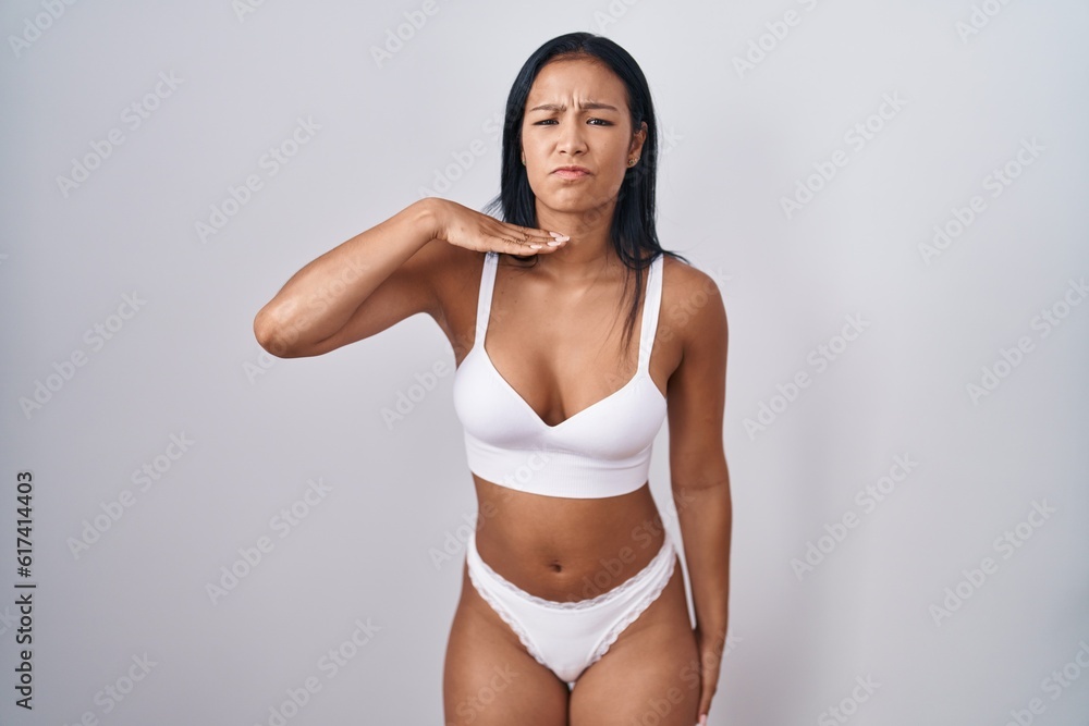 Hispanic woman wearing lingerie cutting throat with hand as knife, threaten aggression with furious violence Hispanic woman wearing lingerie cutting throat with hand as knife, threaten aggression with furious violence