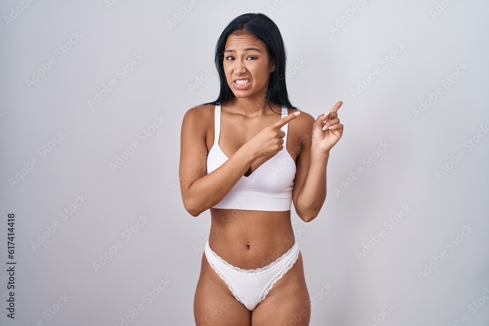 Hispanic woman wearing lingerie pointing aside worried and nervous with both hands, concerned and surprised expression Hispanic woman wearing lingerie pointing aside worried and nervous with both hands, concerned and surprised expression