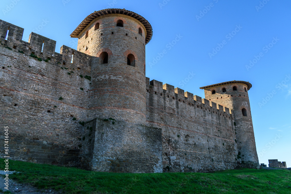 The medieval city of Carcassonne, towers with pointed roofs and solid walls of the fortified buildings, a low angle view. The medieval city of Carcassonne, towers with pointed roofs and solid walls of the fortified buildings, a low angle view.