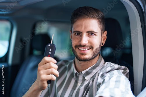 Young caucasian man smiling confident holding key of new car at street