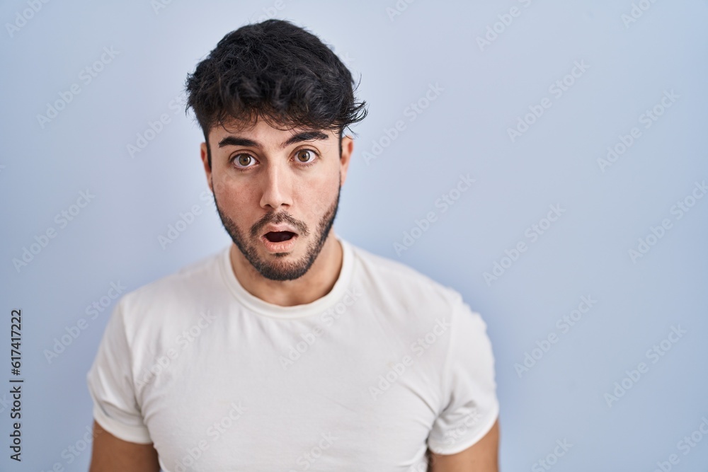Fototapeta premium Hispanic man with beard standing over white background afraid and shocked with surprise and amazed expression, fear and excited face.