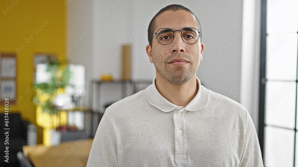 Fototapeta premium Young hispanic man business worker standing with relaxed expression at office