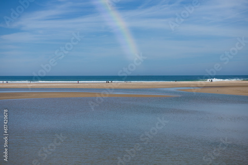 Panoramic view of the beach in the town of conil in cadiz, andalusia, spain. The sky is clear after the storm and you can see the rainbow in the blue sky and people walking. photo