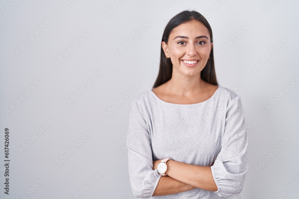 Young hispanic woman standing over white background happy face smiling with crossed arms looking at the camera. positive person. Young hispanic woman standing over white background happy face smiling with crossed arms looking at the camera. positive person.