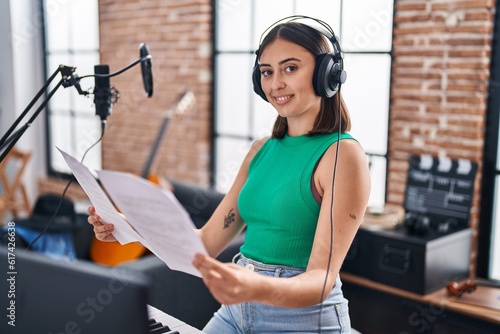 Young hispanic woman musician playing piano keyboard at music studio