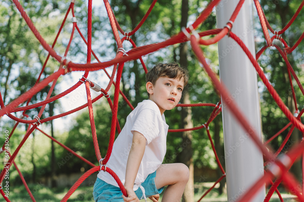 Happy boy child playing in rope spider web at playground. Children's sports. Happy boy child playing in rope spider web at playground. Children's sports.