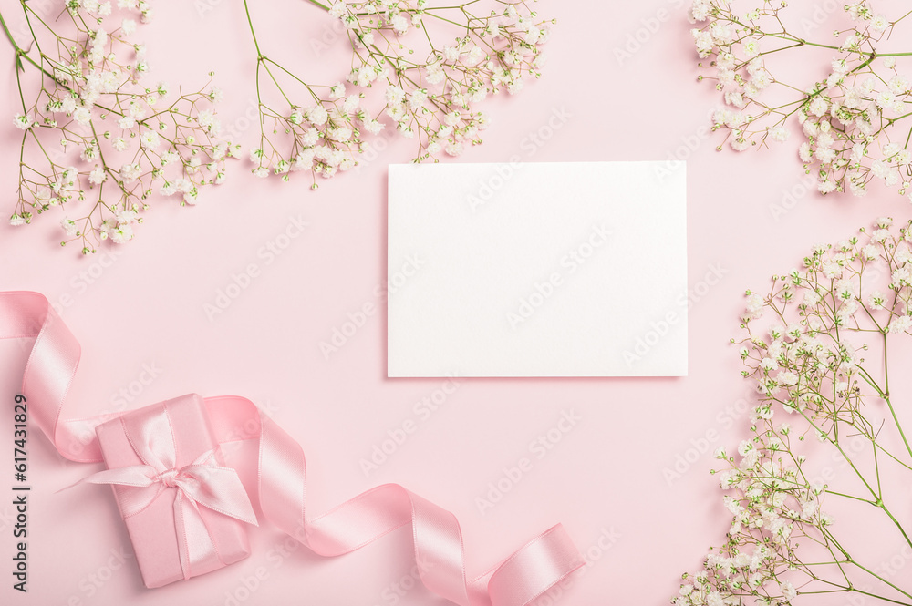 Flat lay composition with empty blank gift box, satin ribbon and gypsophila on pink background. Stylish invitation. Postcard