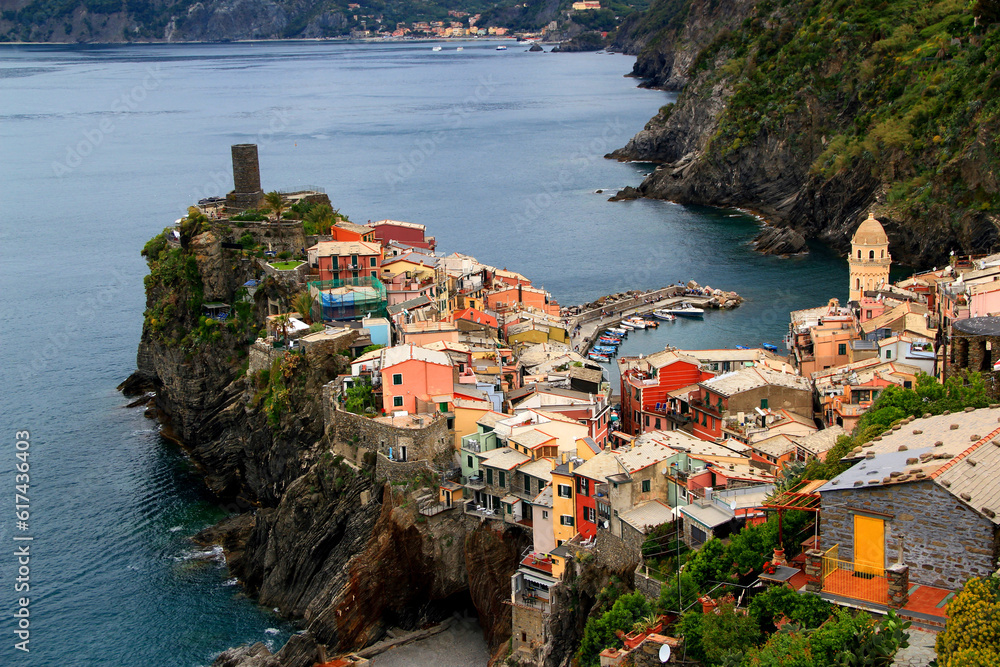 Landscape with a view of the city of Vernazza with the church and the ruins of tower against the background of the mountains and the Ligurian Sea in the Cinque Terre National Park in Italy