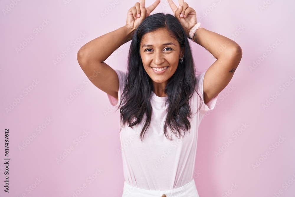 Young hispanic woman standing over pink background posing funny and crazy with fingers on head as bunny ears, smiling cheerful Young hispanic woman standing over pink background posing funny and crazy with fingers on head as bunny ears, smiling cheerful