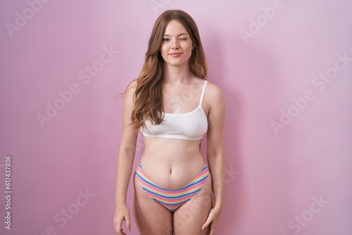 Caucasian woman wearing lingerie over pink background winking looking at the camera with sexy expression, cheerful and happy face. © Krakenimages.com