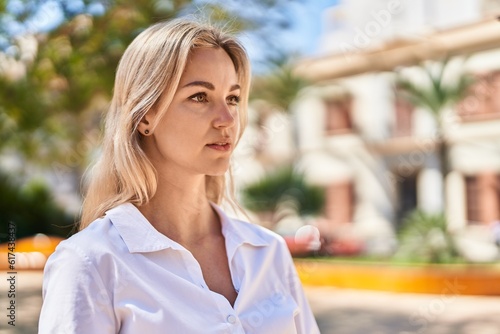 Young blonde woman with relaxed expression standing at park