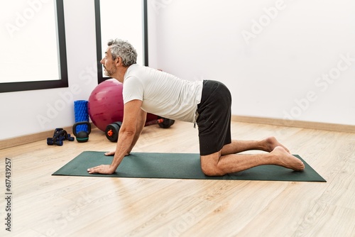 Middle age grey-haired man stretching back at sport center