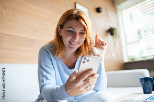 Mid adult woman using a smart phone at home