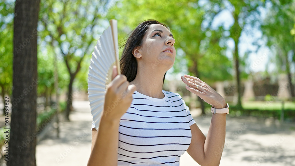 Middle eastern woman using handfan suffering for hot weather at park Middle eastern woman using handfan suffering for hot weather at park