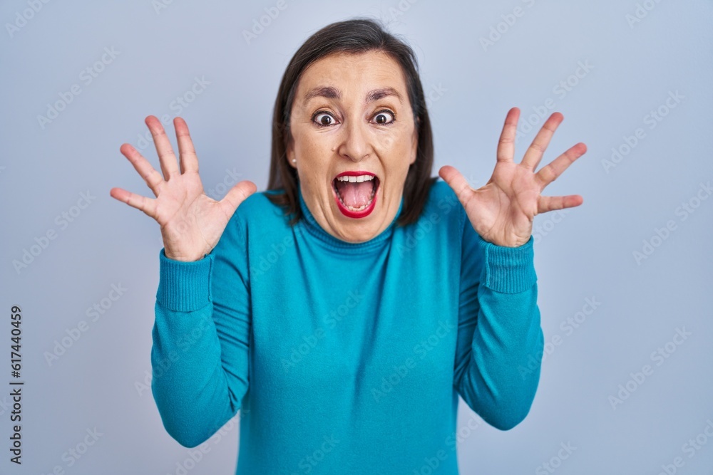 Middle age hispanic woman standing over isolated background celebrating crazy and amazed for success with arms raised and open eyes screaming excited. winner concept Middle age hispanic woman standing over isolated background celebrating crazy and amazed for success with arms raised and open eyes screaming excited. winner concept