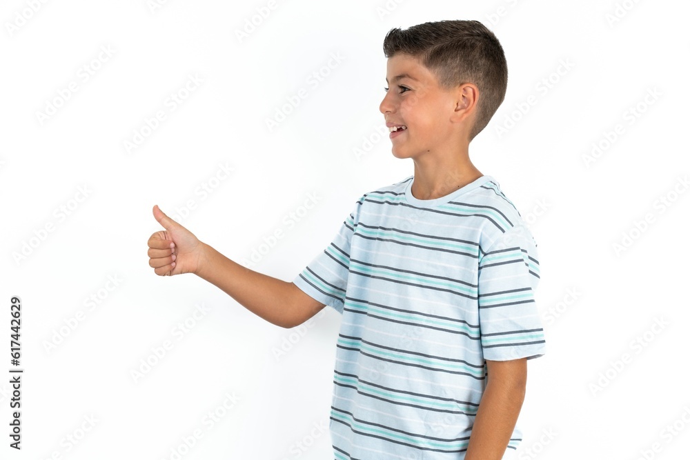Little hispanic boy wearing striped T-shirt Looking proud, smiling doing thumbs up gesture to the side. Good job! Little hispanic boy wearing striped T-shirt Looking proud, smiling doing thumbs up gesture to the side. Good job!