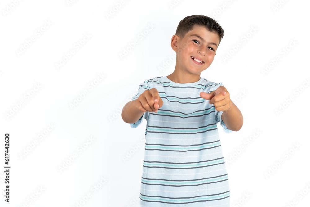 Little hispanic boy wearing striped T-shirt pointing fingers to camera with happy and funny face. Good energy and vibes. Little hispanic boy wearing striped T-shirt pointing fingers to camera with happy and funny face. Good energy and vibes.