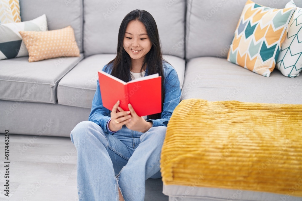 Young chinese woman reading book sitting on floor at home Young chinese woman reading book sitting on floor at home