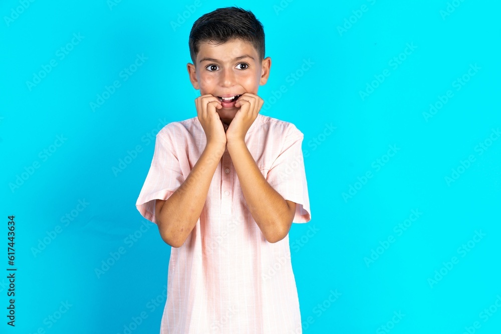 Speechless Little hispanic boy wearing white shirt keeps hands near opened mouth reacts to shocking news stares wondered at camera Speechless Little hispanic boy wearing white shirt keeps hands near opened mouth reacts to shocking news stares wondered at camera