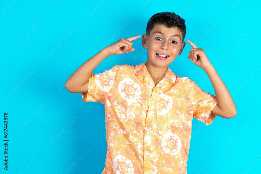 Cheerful Little hispanic boy wearing hawaiian shirt demonstrating hairdo Cheerful Little hispanic boy wearing hawaiian shirt demonstrating hairdo