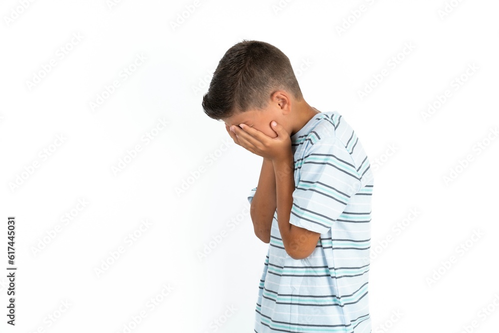 Sad Little hispanic kid boy wearing striped T-shirt crying covering her face with her hands. Sad Little hispanic kid boy wearing striped T-shirt crying covering her face with her hands.