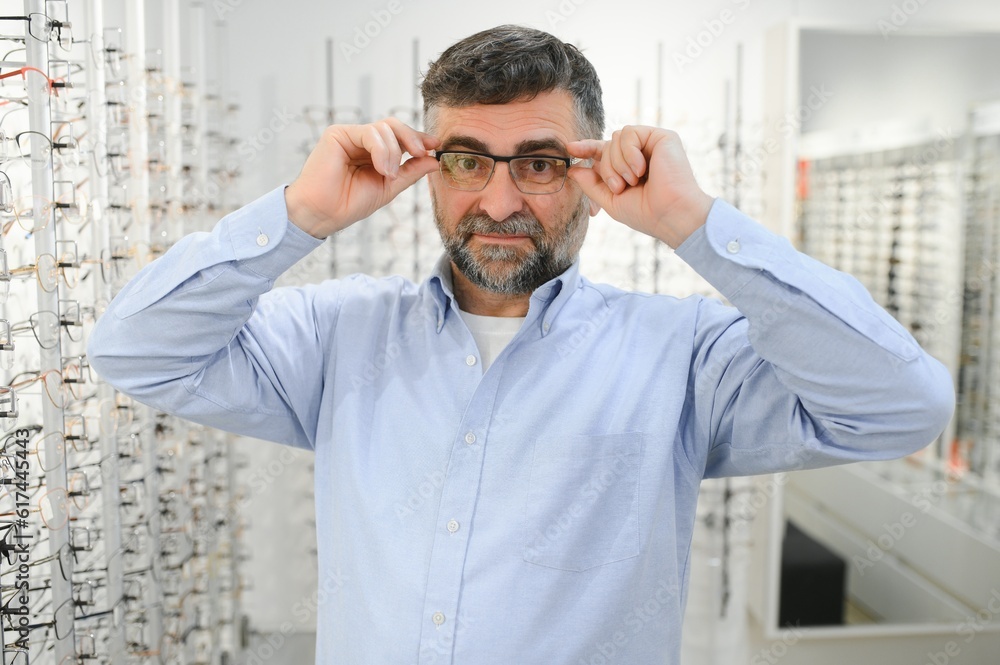 Fototapeta premium male customer choosing glasses in optics store