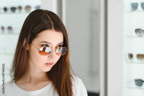 young woman chooses sunglasses for herself in an optics store © Serhii