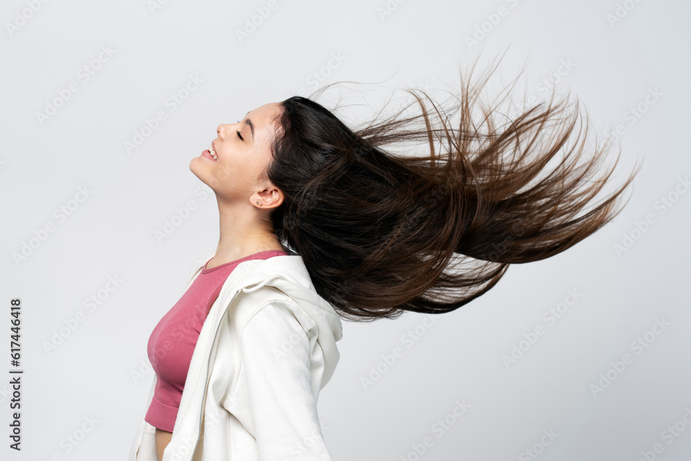 Pretty latin brunette girl with closed eyes, hair flying to sides isolated on gray background