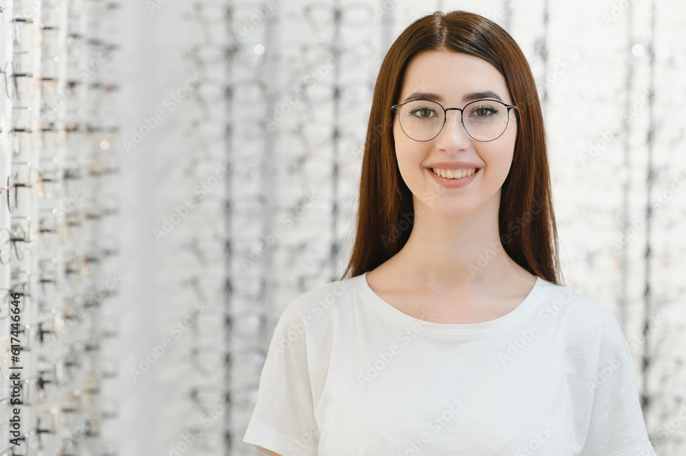 Young Woman with Eyeglasses in Optical Store - Beautiful girl wearing glasses in optician shop Young Woman with Eyeglasses in Optical Store - Beautiful girl wearing glasses in optician shop
