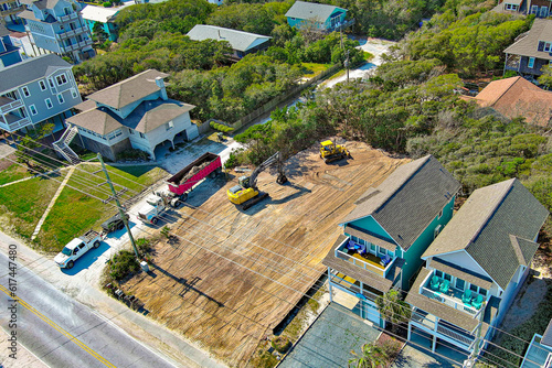 Distant top-down aerial view of a yellow excavator preparing a vacant lot. 