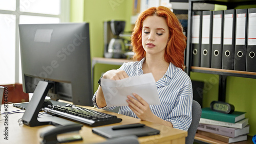 Young redhead woman business worker using computer opening envelope letter at office