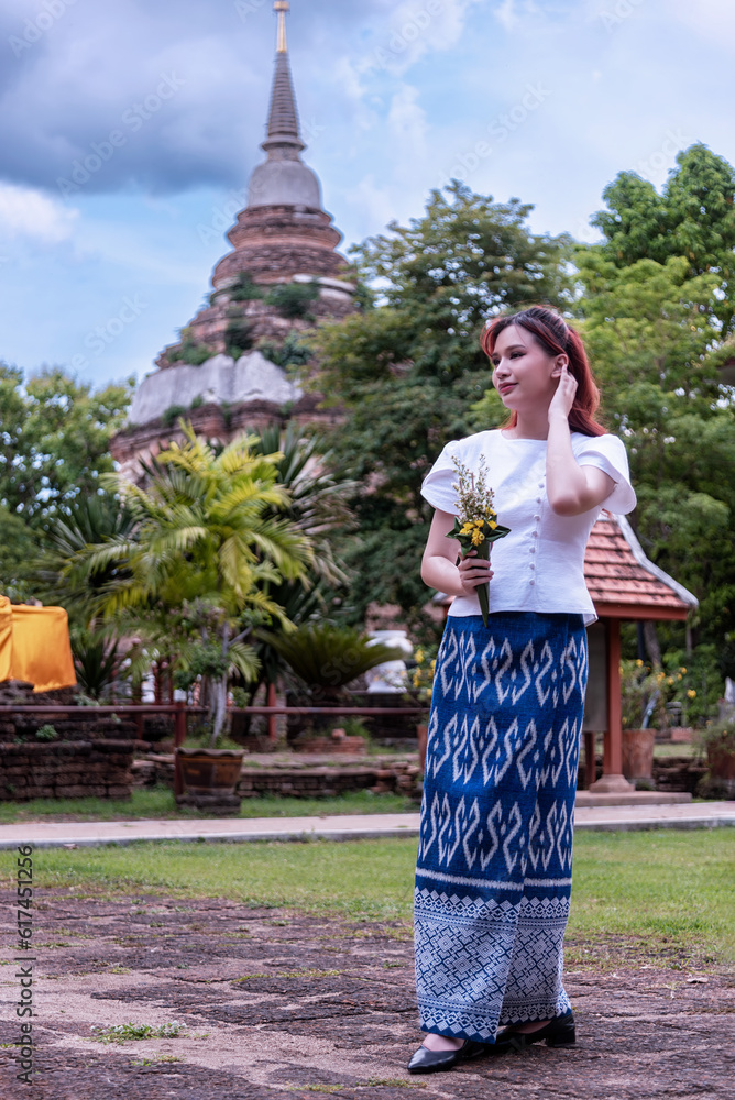 Young Asian women dressed in traditional costumes visit an old temple in Thailand.