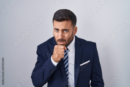 Handsome hispanic man wearing suit and tie feeling unwell and coughing as symptom for cold or bronchitis. health care concept.
