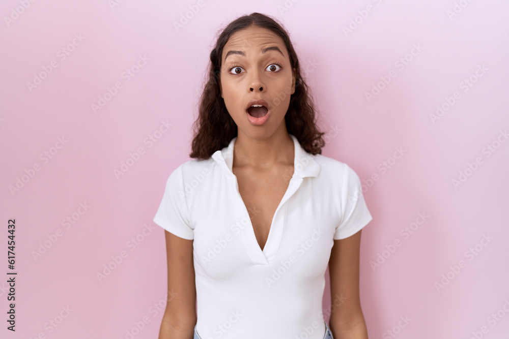 Young hispanic woman wearing casual white t shirt afraid and shocked with surprise and amazed expression, fear and excited face. Young hispanic woman wearing casual white t shirt afraid and shocked with surprise and amazed expression, fear and excited face.