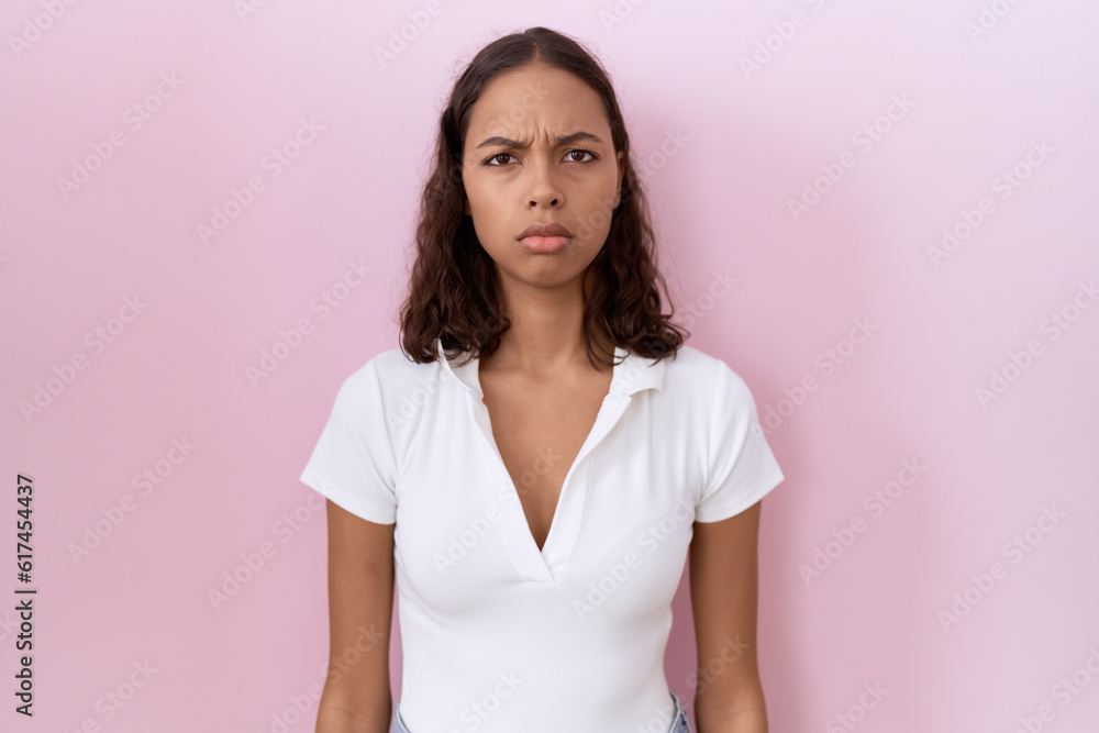Young hispanic woman wearing casual white t shirt skeptic and nervous, frowning upset because of problem. negative person. Young hispanic woman wearing casual white t shirt skeptic and nervous, frowning upset because of problem. negative person.