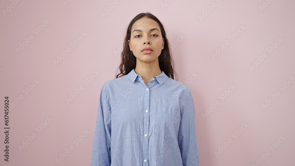 Young beautiful hispanic woman standing with serious expression over isolated pink background Young beautiful hispanic woman standing with serious expression over isolated pink background