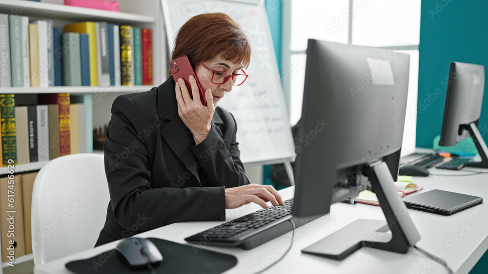 Mature hispanic woman university teacher using computer speaking on the phone at library university Mature hispanic woman university teacher using computer speaking on the phone at library university