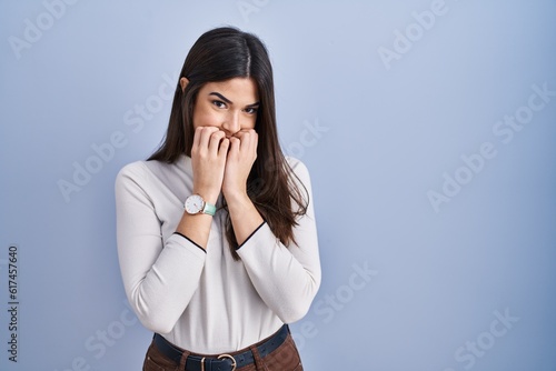 Billede på lærred Young brunette woman standing over blue background laughing and embarrassed gigg