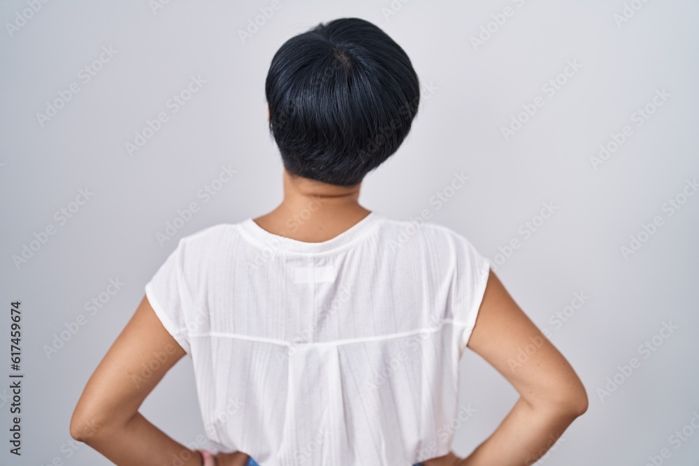 Young asian woman with short hair standing over isolated background standing backwards looking away with arms on body Young asian woman with short hair standing over isolated background standing backwards looking away with arms on body